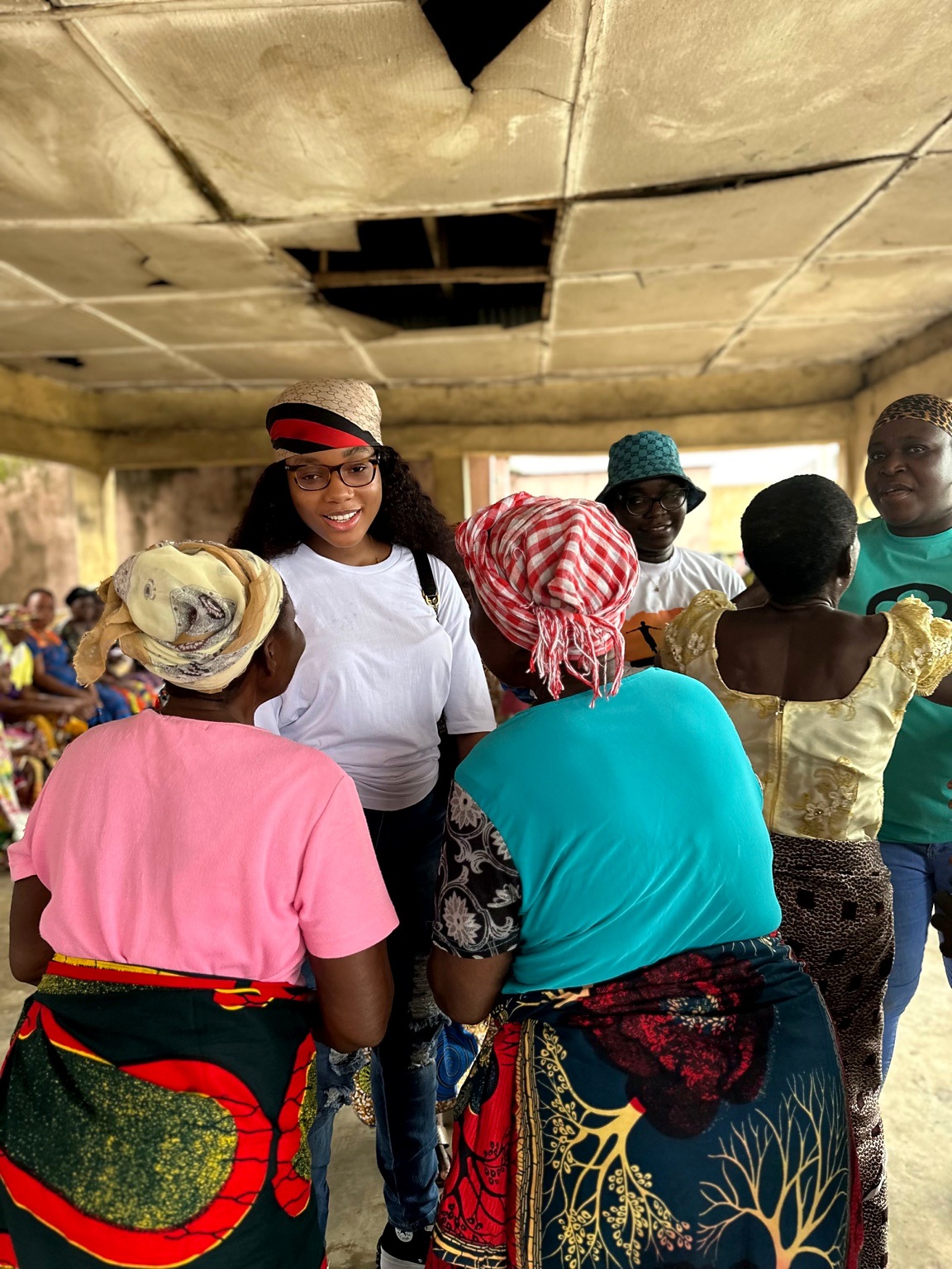 A smiling woman in a white shirt talks with older women gathered around her.